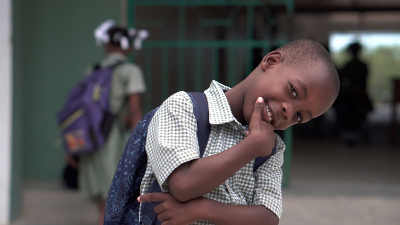 Happy schoolboy with backpack, smiling and posing at school, child education in Africa.